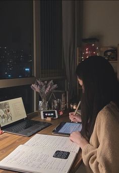 a woman sitting at a desk with an open laptop computer and papers in front of her