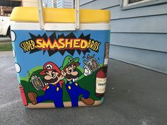 a cooler sitting on the side of a house with two cartoon characters painted on it