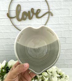 a person holding up a heart shaped bowl with the word love in front of it