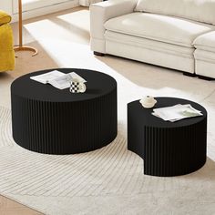 two black coffee tables sitting on top of a rug in front of a white couch