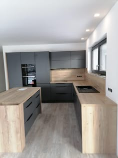 an empty kitchen with wooden counter tops and gray cabinets