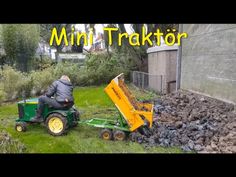 a man riding on the back of a green tractor