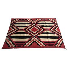 a red, black and white rug with geometric designs on the bottom half of it