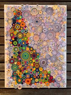 a painting made out of different colored circles on a wooden surface with wood planks in the background