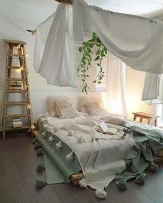 an unmade bed in a room with white drapes hanging from it's ceiling