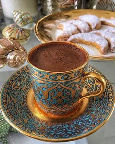 a cup of hot chocolate sitting on top of a saucer next to a plate with pastries