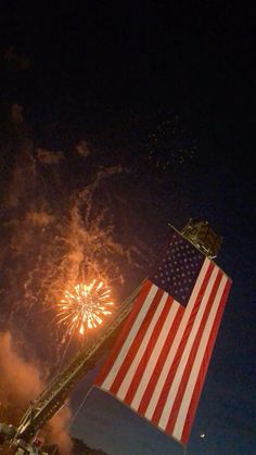 fireworks and an american flag are lit up in the night sky