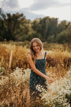 a woman standing in tall grass smiling at the camera