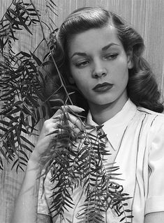 a black and white photo of a woman holding a plant