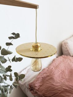 a bed with a pink comforter and a gold lamp hanging from it's side