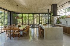 a kitchen and dining area with large windows in the middle, surrounded by wooden furniture