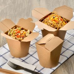 there are two boxes with noodles in them on the table next to utensils