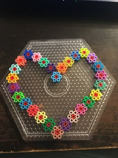 a plastic tray with colorful beads arranged in the shape of a heart on top of it