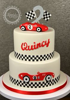 a three tiered cake with a racing car on top and the number two is made out of fondant