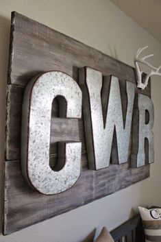 a wooden sign with the word cwr hanging on it's wall above a crib