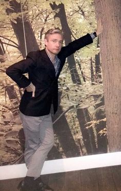 a man standing in front of a wall with trees on it