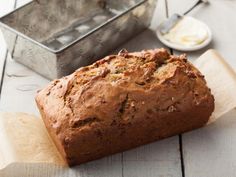 a loaf of bread sitting on top of a wooden cutting board next to a metal pan