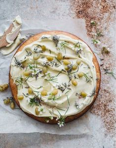 a cake with white frosting and green olives on top, sitting on wax paper