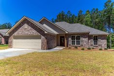 a brick and stone house in the middle of a grassy area with trees behind it