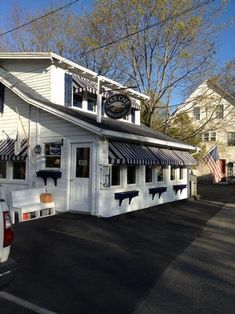 a truck parked in front of a white building with an american flag on it's roof