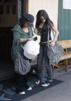 two women standing next to each other near a building