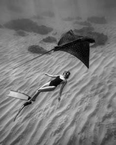 a woman is floating in the sand with a kite