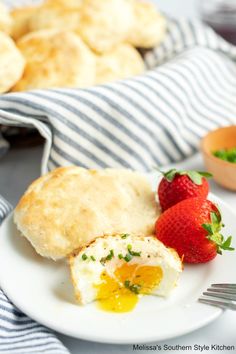 a white plate topped with eggs and bread next to strawberries