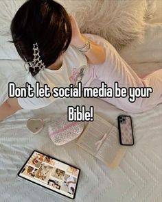 a woman laying on top of a bed next to an open book and cell phone