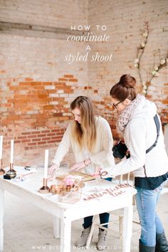 two women are standing at a table with candles and cakes on it, one is cutting the cake