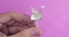 a person holding up a piece of paper with an origami bird on it