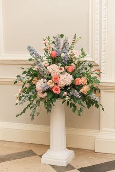 a tall white vase filled with lots of flowers