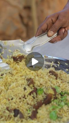 a person scooping food out of a large pan