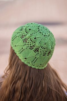 the back of a woman's head wearing a green crocheted hat