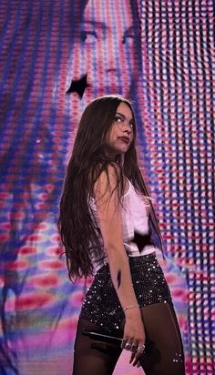 a woman in black and white outfit standing on stage with her hands behind her back