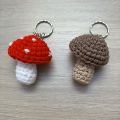 two crocheted keychains with mushrooms on them sitting on top of a table