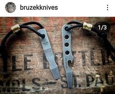 two knives sitting on top of a wooden table next to a black cord and an old sign that says bruzeknives