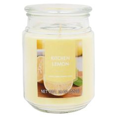 a candle that is sitting on a white surface with lemons in the back ground