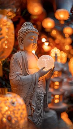 a buddha statue holding a light in front of many lit up lanterns and candles behind it