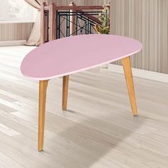 a pink table sitting on top of a hard wood floor next to a wooden staircase