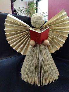 an origami angel holding a red book