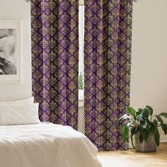 a bed room with a neatly made bed and purple curtains