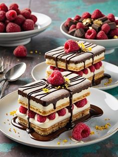 three desserts on plates with raspberries and chocolate drizzled over them