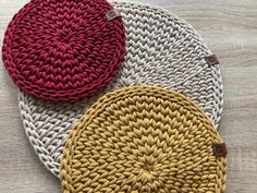 three round knitted placemats sitting on top of a wooden table next to each other