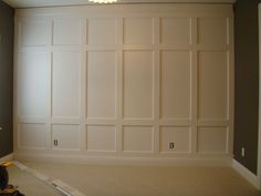 an empty room with white paneling on the walls