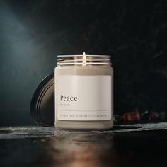 a white candle sitting on top of a table next to a black wall and floor