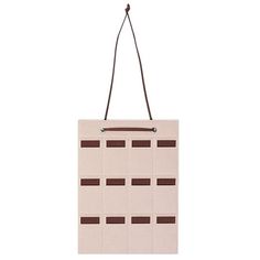 a white bag with brown squares hanging from it's side on a corded hanger