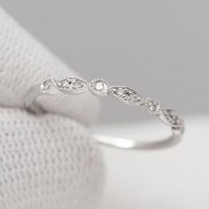 a white gold wedding ring with diamonds on it's side, sitting on top of a cloth