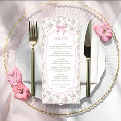 a table setting with pink flowers and silverware on it, including a menu card