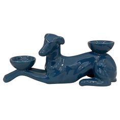 a blue dog figurine sitting on the ground with a bowl in it's mouth