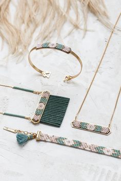 three pieces of jewelry sitting on top of a white table next to a hairbrush